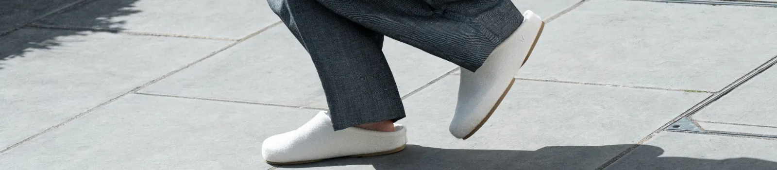 White Round-Toe Clog Mules in motion on a sunlit sidewalk